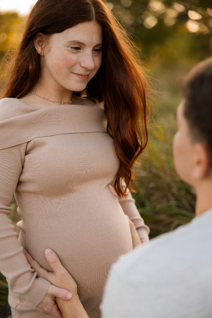 Maternity photo of mom and dad looking at each other and dad holding onto baby bump maternity session in delafield wisconsin