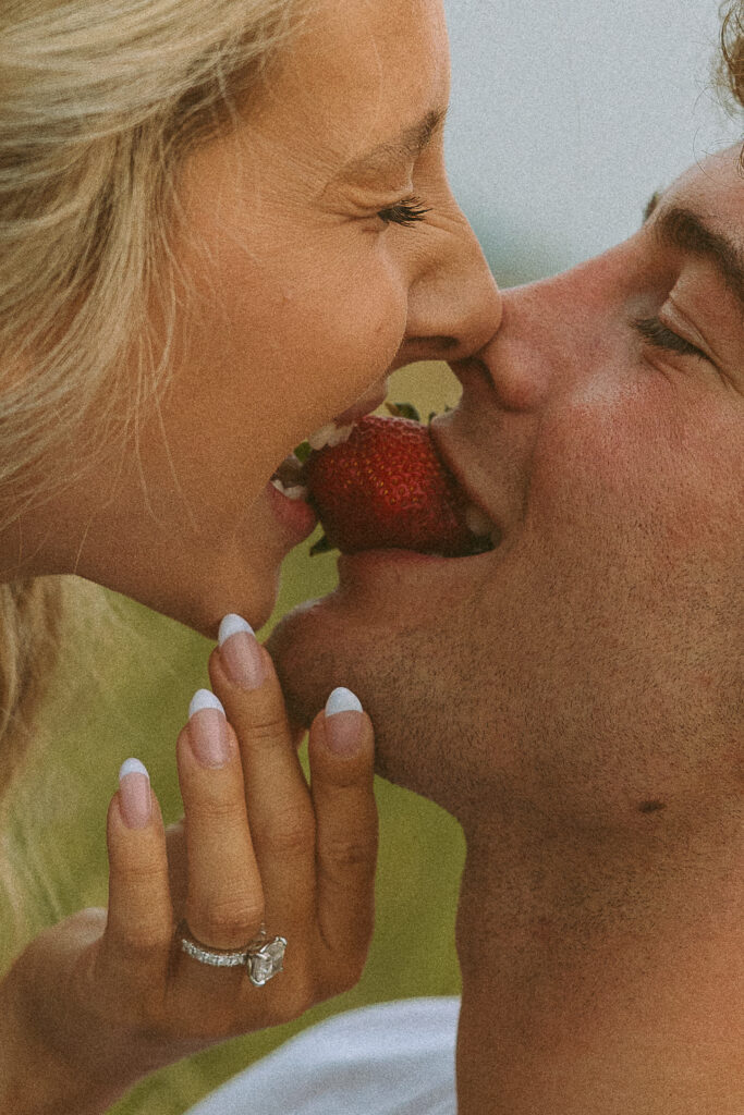 Close up of a couple sharing a strawberry during a romantic outdoor photoshoot