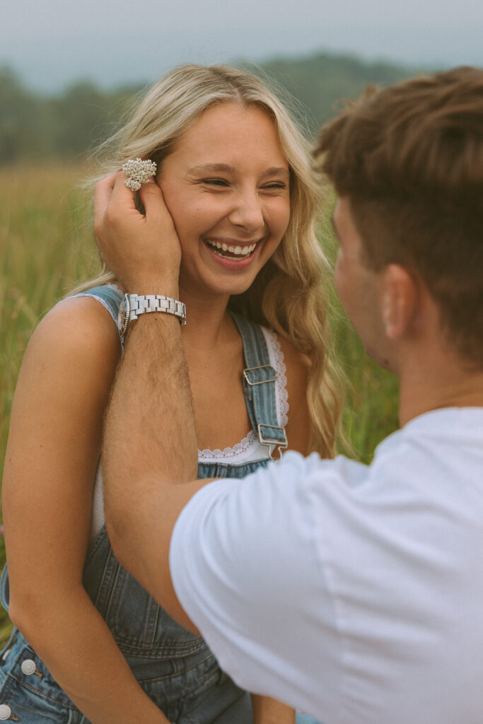 Candid portrait of a woman laughing as her partner gently tucks a flower into her hair