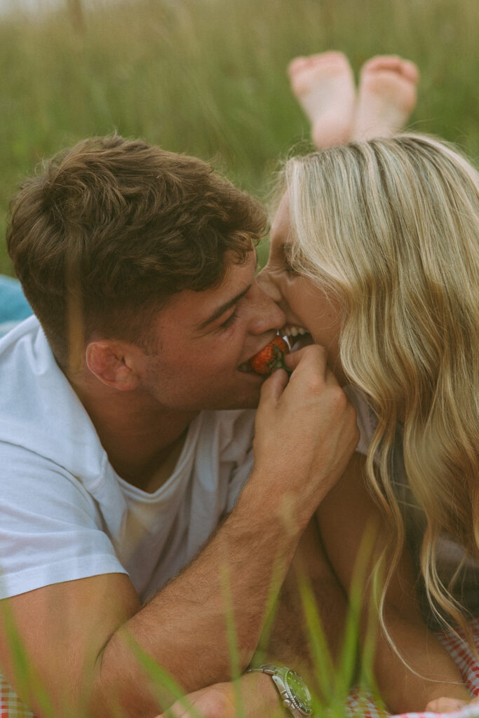 Couple sharing a strawberry during a playful themed couples photoshoot