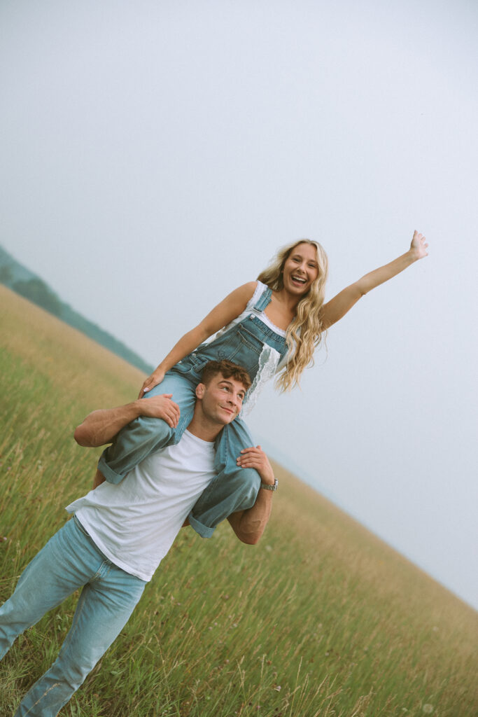 Playful couples photography in Wisconsin with a woman riding on her partner's shoulders
