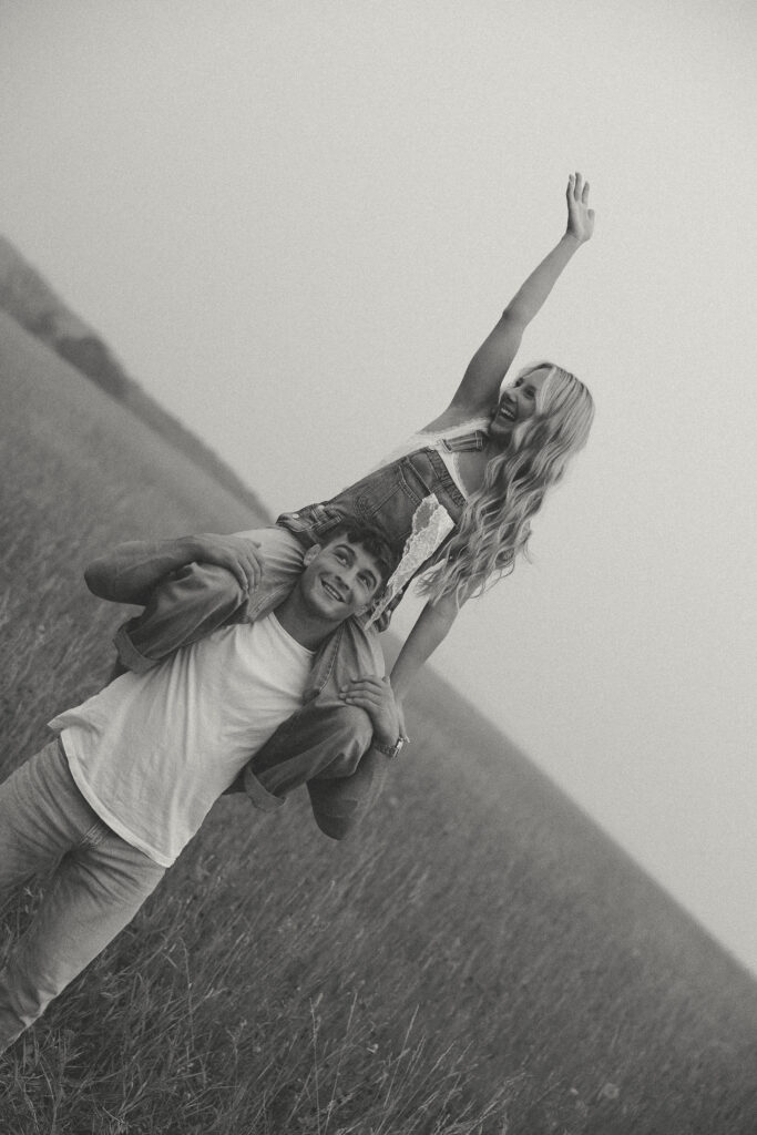 Black and white portrait of a couple playfully posing together in a field

